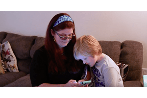 Mother and son looking at teleburn app on phone