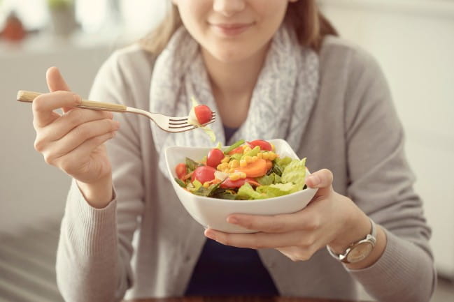 A person eating a bowl of salad.