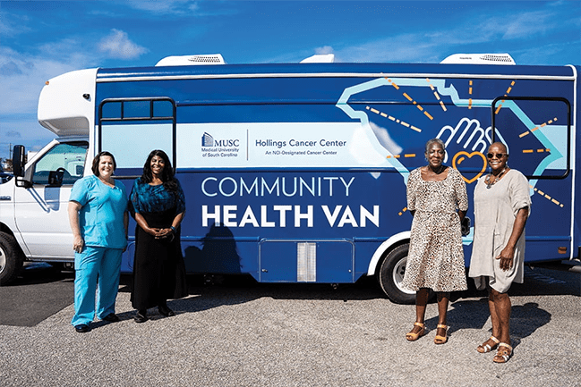 Four women posing in front of a community health van